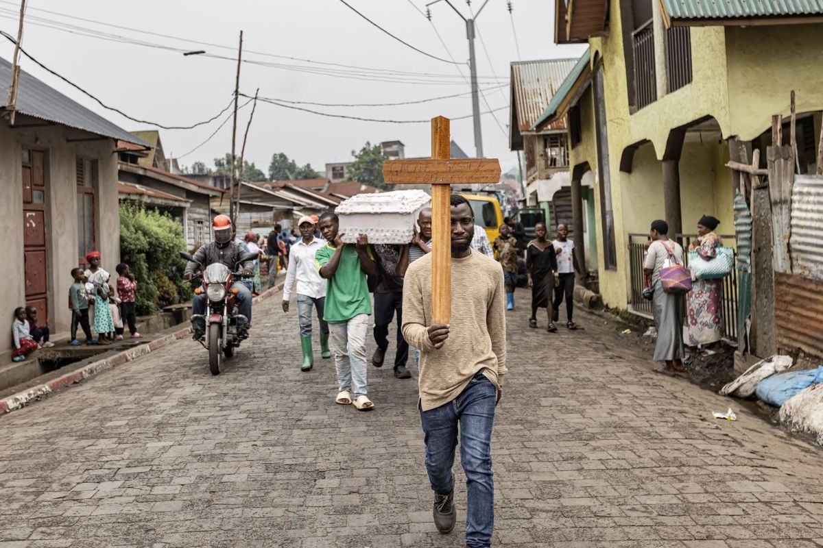  A man carries a cross during a funeral procession towards the ITIG Graveyard in Goma on February 4, 2025 where fresh graves have been dug to accomodate victims of the recent violence.