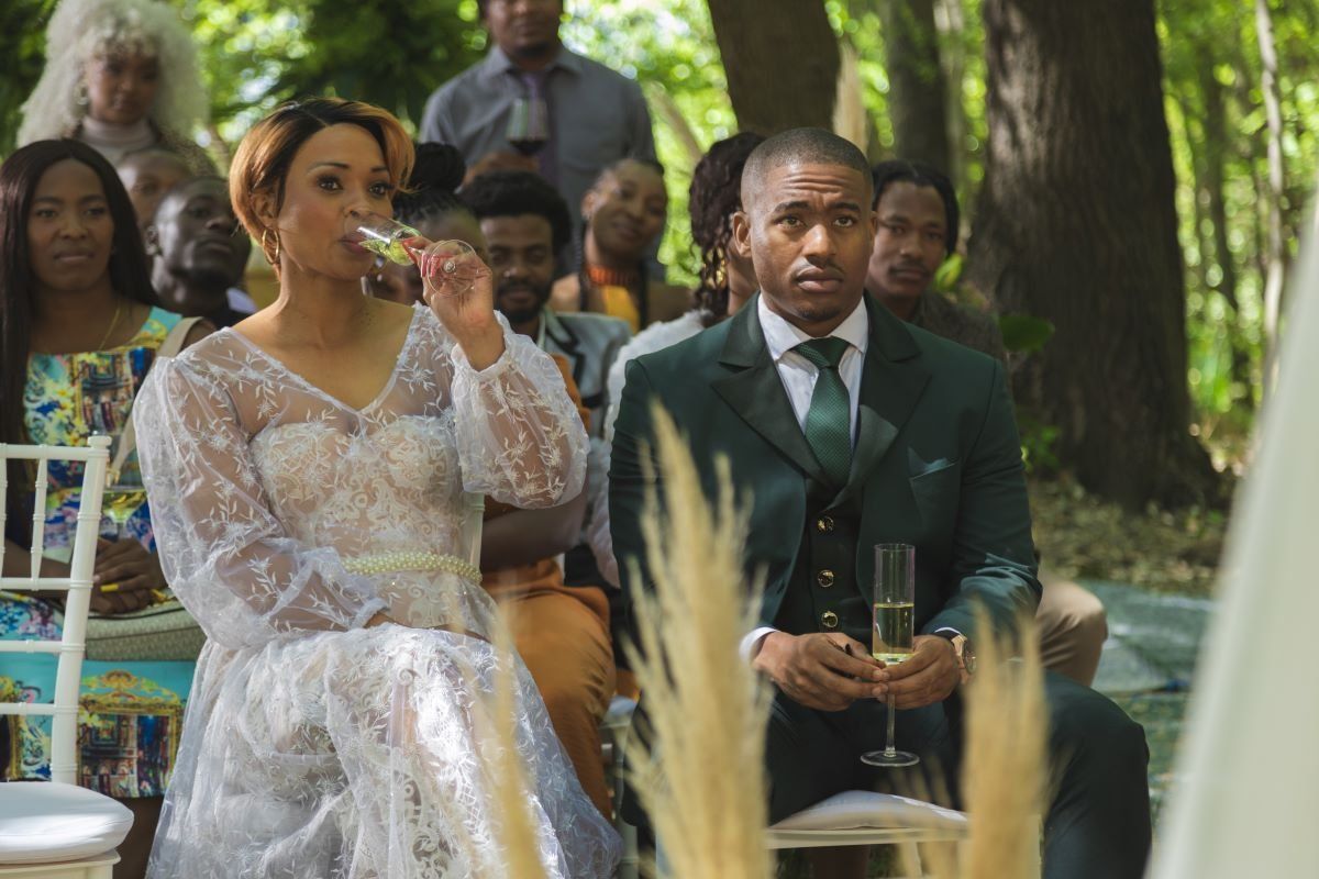 A still from ‘Savage Beauty’ season two showing a man and a woman sitting together at an outdoor event.