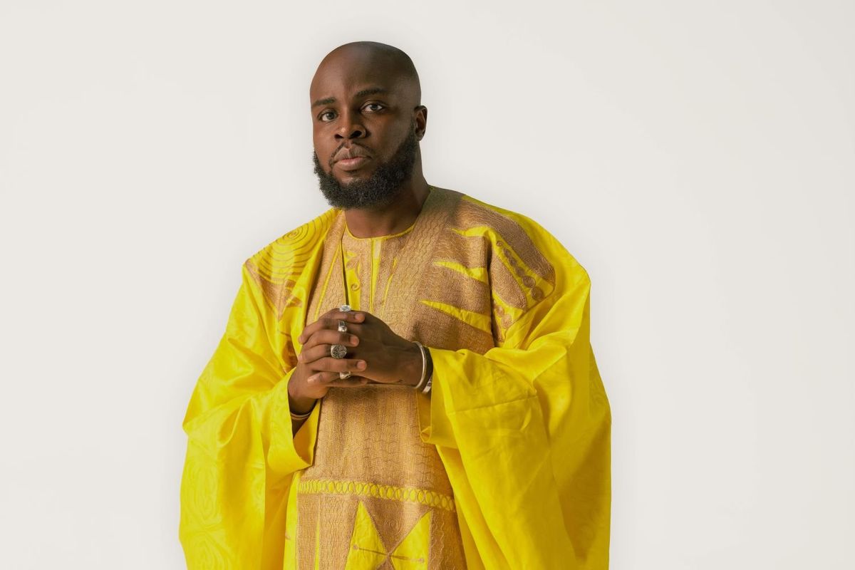 Ghanaian rapper M.anifest wears a yellow outfit in a press image for his new album.