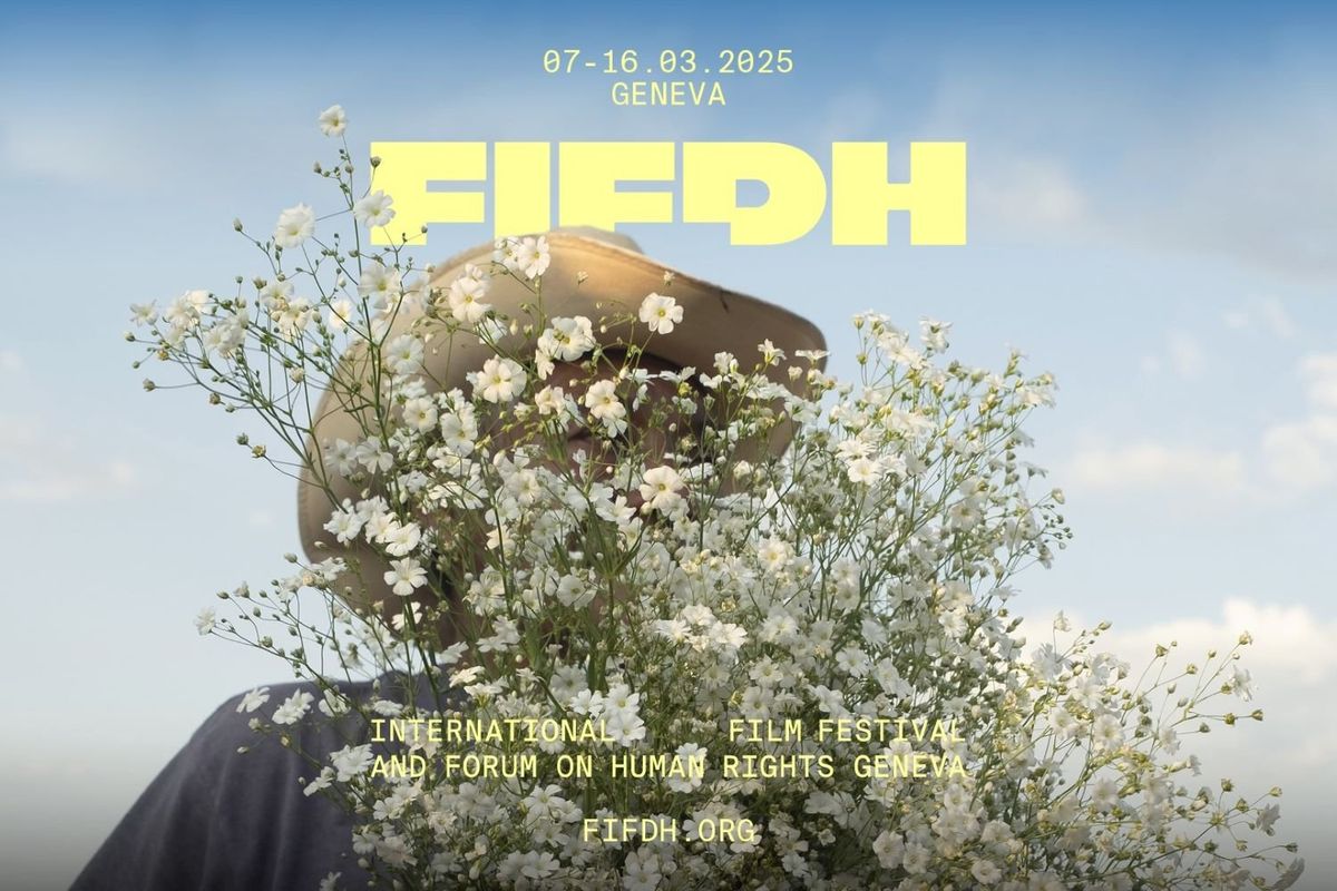 In front of a blue sky, a man wearing a beige hat is holding white flowers that are hiding his face. In yellow letters, the caption above his head reads FIFDH.
