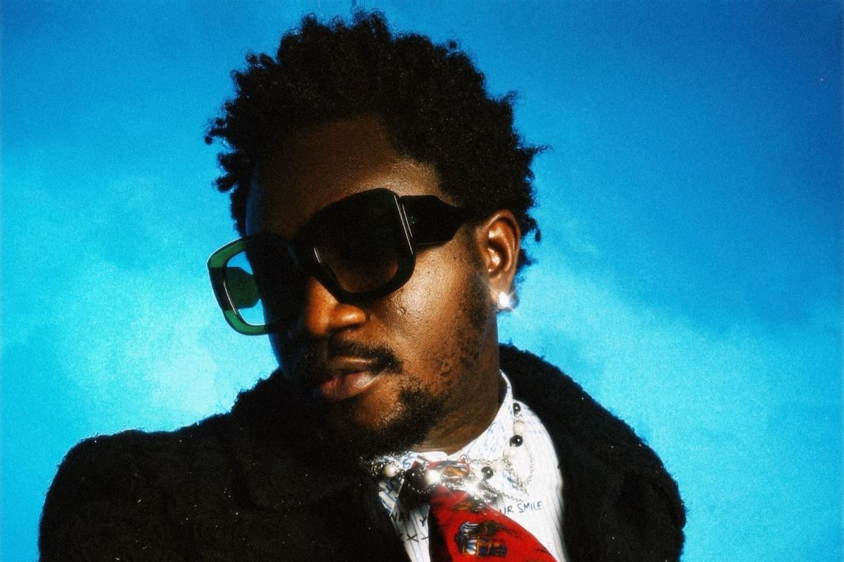 Nigerian skitmaker and musician Nasboi poses in sunglasses and suit. 