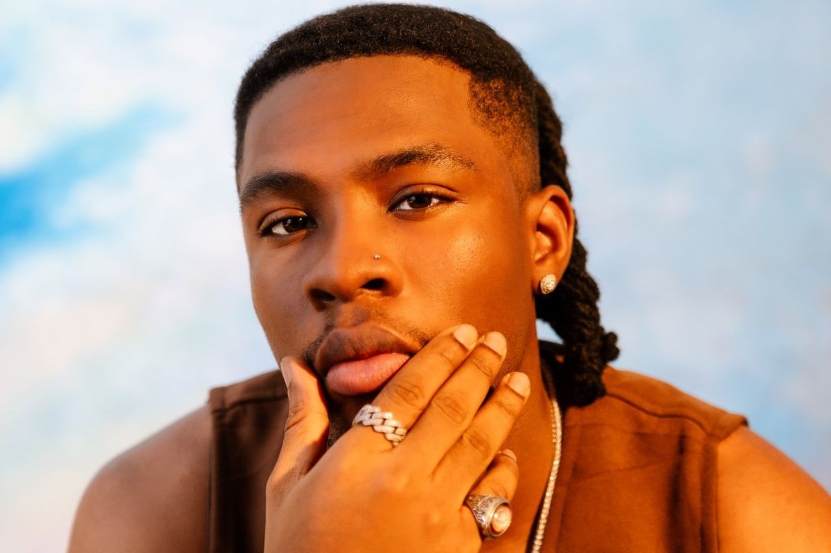 Nigerian star Joeboy dons dreadlocks and poses while staring directly at the camera.