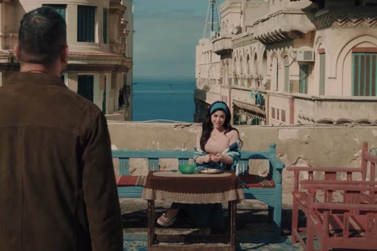 Screengrab from Ramadan TV series Beit El Rifai showing a man approaching a woman sitting at a table outside on a balcony.
