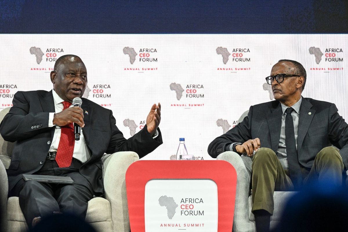 South African President Cyril Ramaphosa speaks into a microphone while gesturing with his hand, seated beside Rwandan President Paul Kagame, who listens intently with his hands folded. The two leaders share the stage at the 2025 Africa CEO Forum Annual Summit, with the forum’s logo and branding visible in the background.