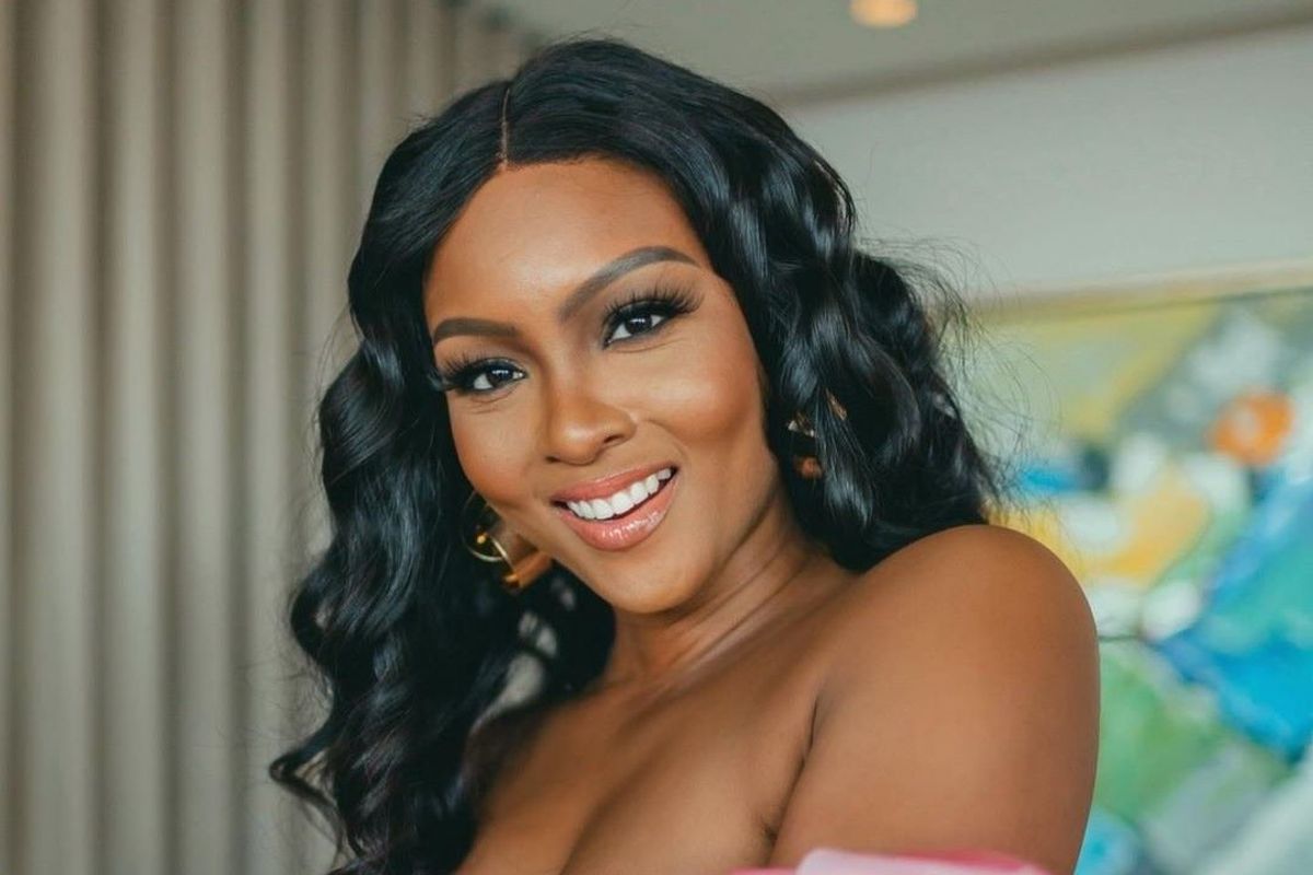 ‘The Smart Money Woman’ star Osas Ighodaro poses for a photo in a red dress with pink sleeves.