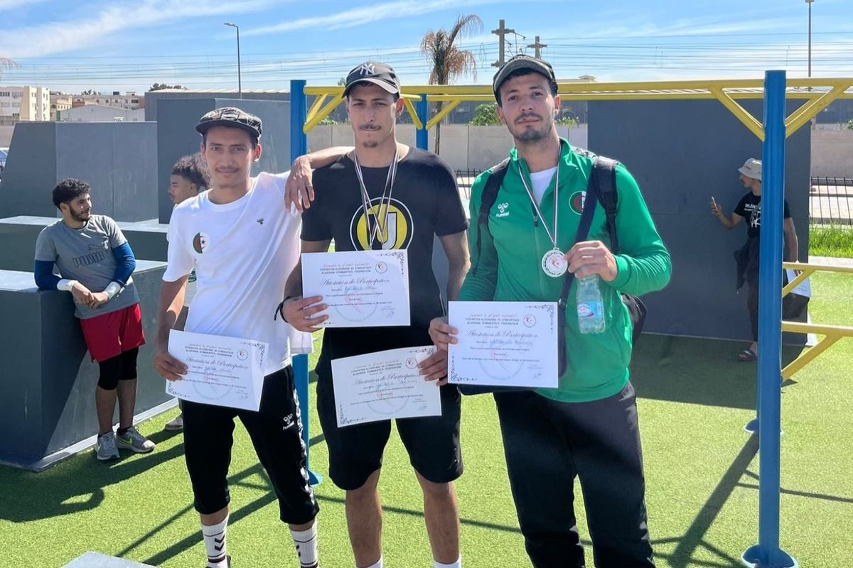 Three parkour athletes pose for a photo on a podium, holding certificates and wearing medals.