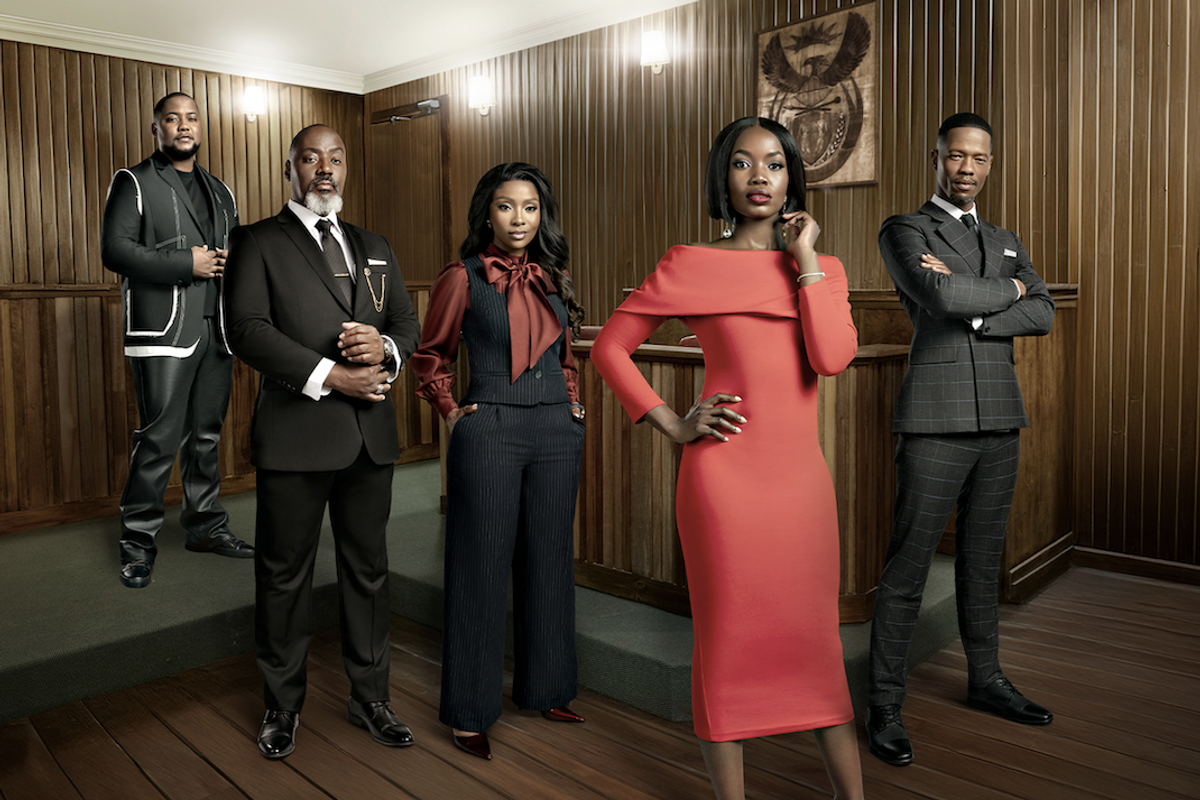 A photo of the cast of 'Love, Law and Betrayal' standing in a wood-paneled courtroom, dressed in formal attire.