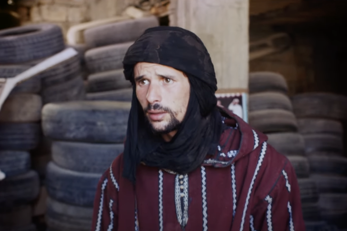 A still from ‘So What If The Goats Die’ showing actor Fouad Oughaou with a pile of used tyres behind him.