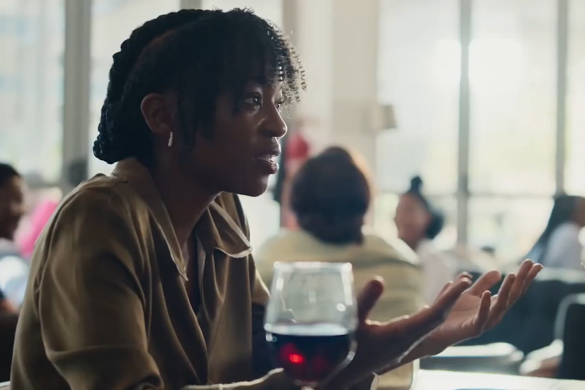 A woman gestures across a table at a restaraunt. 