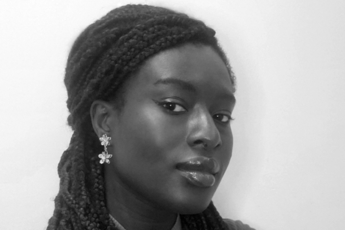 A woman standing with her arms crossed and looking at the camera sideways.